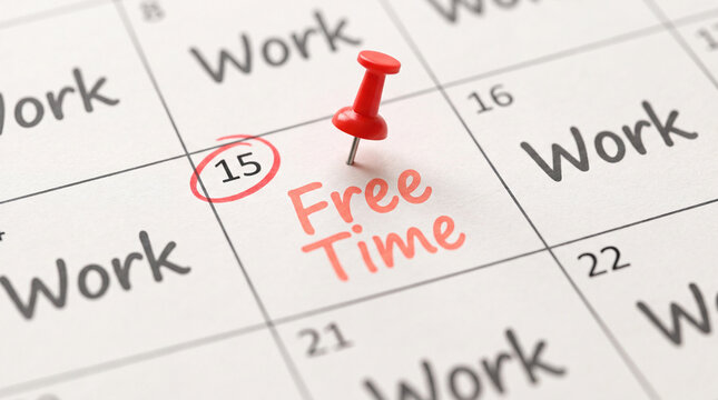 A close-up calendar grid showing the text Free Time written in red with a red pushpin marking the date, surrounded by work schedules.