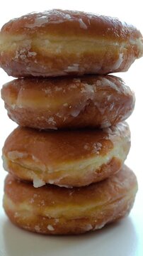Vertical slow motion shot of stacked donuts spinning against white background