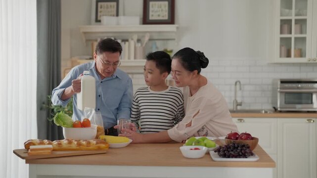 Family kitchen breakfast preparation, father pour milk, mother and son, indoor home scene, healthy food, happy family in bright home interior with son and mother smiling
