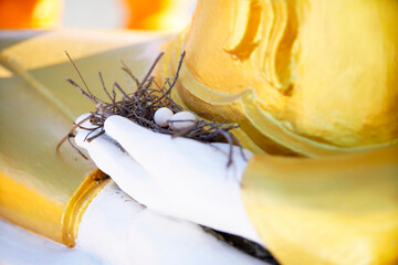 Fototapeta premium Close-up of a nest with eggs on religious statue's base showing faith and spirituality