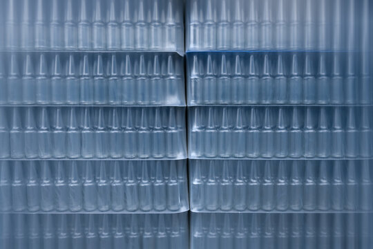 Rows of Small Glass Bottles Packaged in Cellophane. Motion blur is used for dynamics.