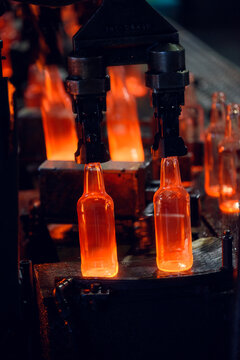 Industrial Robot Gripper Holding Hot Glowing Glass Bottles