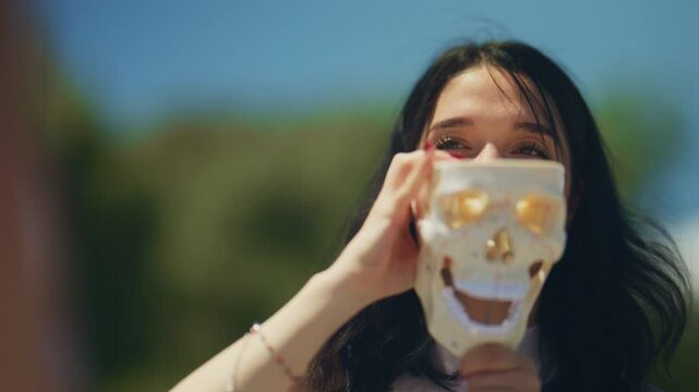 Young school friends examine a human skull model together outdoors. Students engage in a playful yet educational interaction with an anatomical skull.