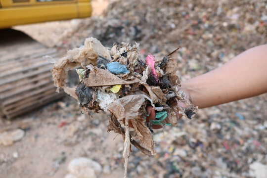 A waste processing facility with a large pile of shredded plastic and mixed municipal waste, representing material prepared for sorting, recycling, or refuse-derived fuel production.