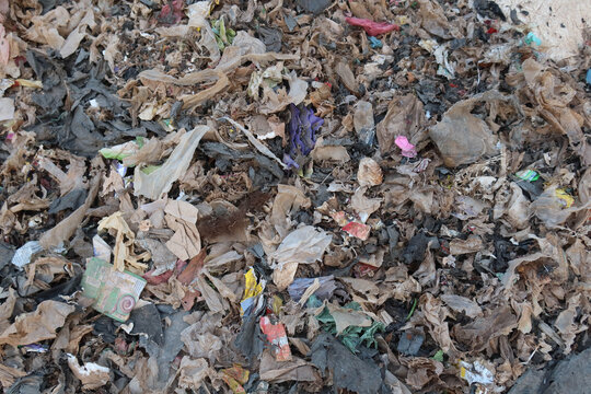 A waste processing facility with a large pile of shredded plastic and mixed municipal waste, representing material prepared for sorting, recycling, or refuse-derived fuel production.