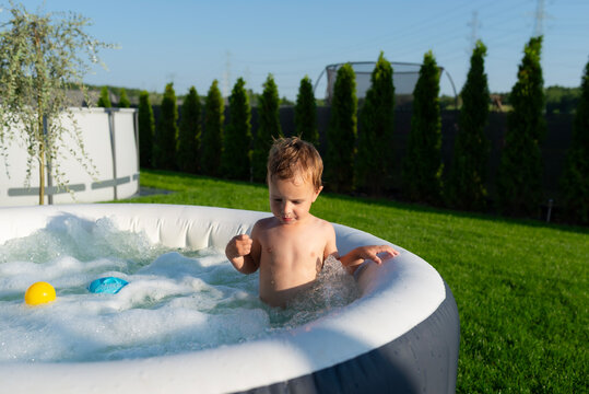 Toddler boy playing in inflatable backyard hot tub