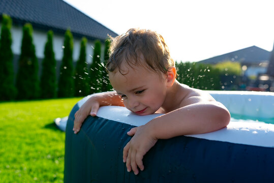 Toddler boy playing in inflatable pool during summer