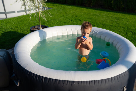 Young boy playing with ball in outdoor hot tub