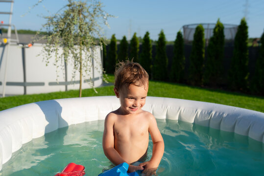 Toddler boy playing in inflatable pool during summer