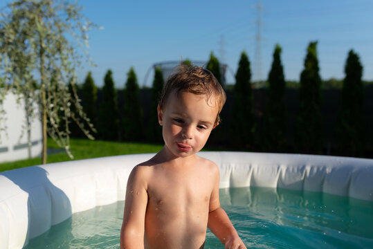 Toddler boy playing in outdoor inflatable pool