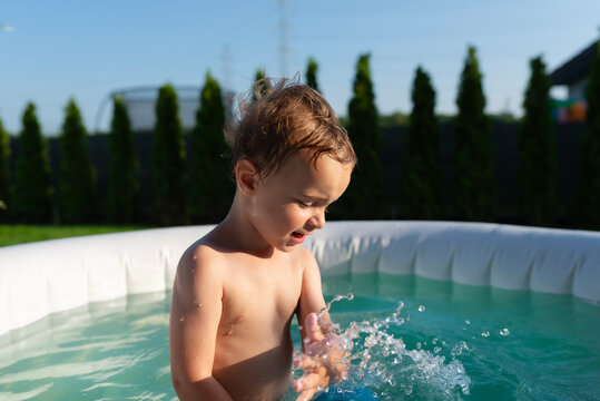 Little boy splashing water in inflatable pool