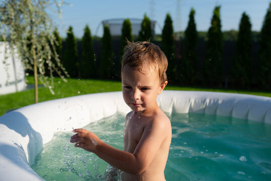 Young boy playing splashing water in inflatable backyard pool