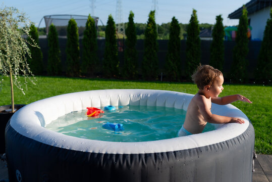 Boy playing with water in inflatable garden hot tub