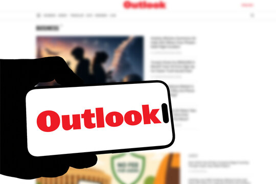 Kiel, Germany - 08-19-2026: Smartphone displaying Indian news media company Outlook India logo in front of companys webpage