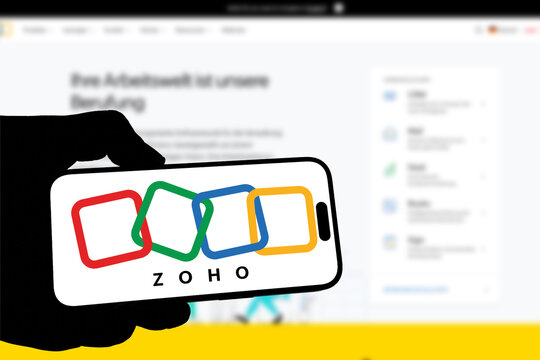 Kiel, Germany - 08-19-2026: Smartphone displaying Indian business software company Zoho logo in front of companys webpage