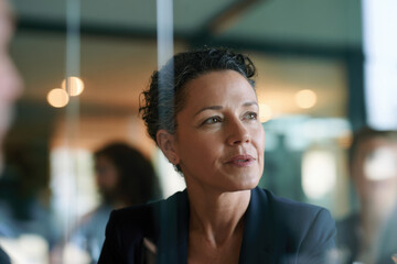 Obraz premium A mature woman is captured in a moment of introspection, engaged in deep thought within a corporate environment, representing focus and professionalism.