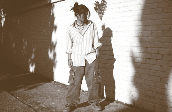 Young Asian woman model standing against brick wall with dran heart