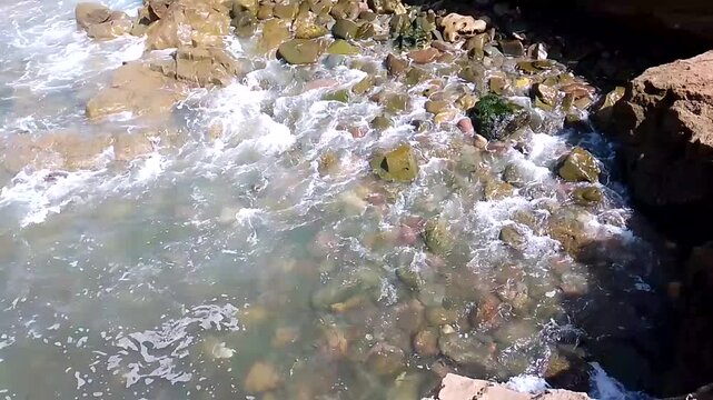 High Angle Waves Foaming Over Wet Pebble Shore Rocks