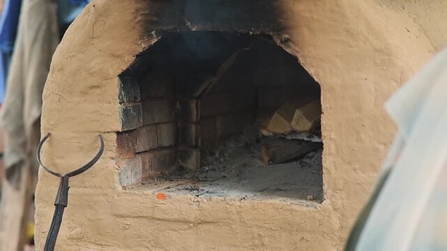 A group of individuals engages in traditional crafts near a clay oven, typical of 11th-century Eastern Europe