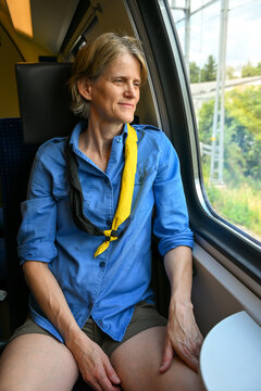 Woman wearing her old scout shirt and neckerchief while travelling by train in Switzerland