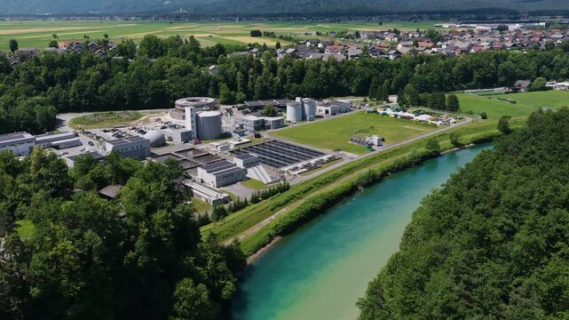 The picture shows a large wastewater treatment plant with settling tanks and filtration systems.