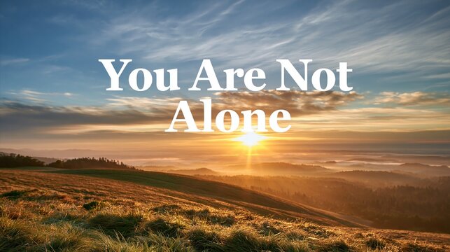Photograph banner, sunrise over calm hills symbolizing hope and new beginnings, bold text overlay reading "You Are Not Alone"
