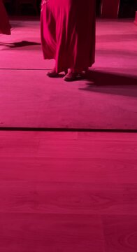 Vertical detail video of flamenco dancing: legs, feet, and dynamic pink skirts in motion