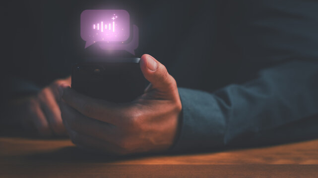 Man holding smartphone with glowing artificial intelligence voice message icon. AI audio technology, digital communication, sound wave, and podcast network concept for business.