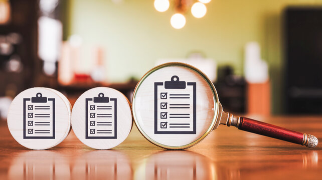 Magnifying Glass Examining a Business Checklist for Quality Control and Audit Analysis on Wooden Table