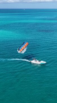 Parasailing In Providenciales Turks And Caicos United Kingdom. Thrilling Adventure With Speedboat Paragliding In Turquoise Ocean. Summer Backgrounds. Bay Water Landscape.