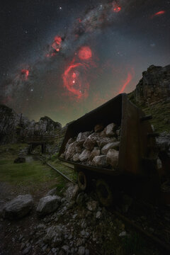 View of an old mining cart filled with rocks at the Lakes of Covadonga under a vibrant starry night sky with the Milky Way in Asturias, Spain.