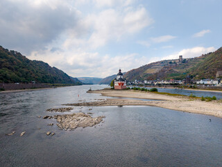 Fototapeta premium A view of the Pfalzgrafenstein Castle on the Rhine River during low water at Kaub, surrounded by hills, vineyards, and the castle Gutenfels
