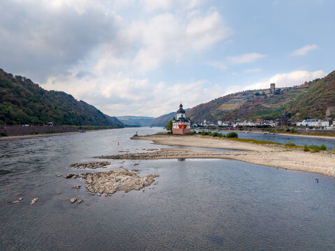 A view of the Pfalzgrafenstein Castle on the Rhine River during low water at Kaub, surrounded by hills, vineyards, and the castle Gutenfels