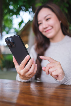 Vertical blurred image of a woman holding and using mobile phone in the outdoors