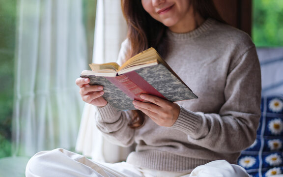 Closeup image of a woman reading a book at home