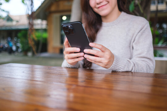 Closeup image of a woman holding and using mobile phone in the outdoors