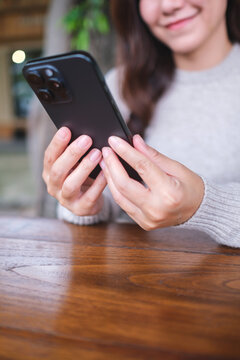 Vertical closeup image of a woman holding and using mobile phone in the outdoors