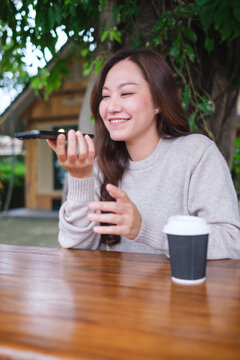 Vertical image of a woman holding smart phone and using voice messaging, talking with ai assistant for Artificial intelligence concept