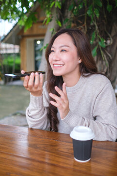 Vertical image of a woman holding smart phone and using voice messaging, talking with ai assistant for Artificial intelligence concept