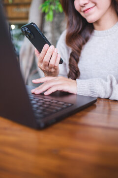 Vertical closeup image of a businesswoman using smart phone and laptop computer