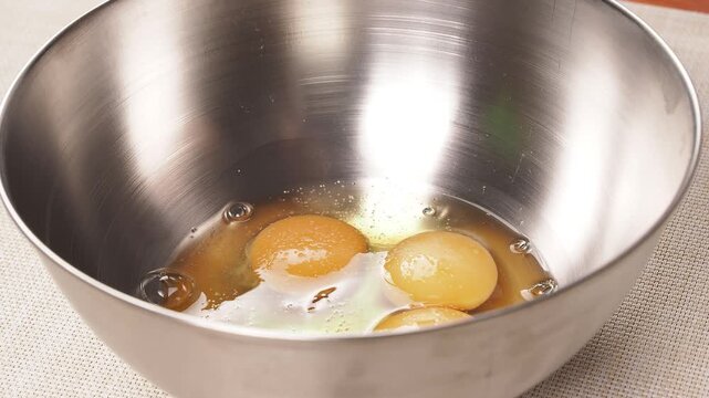 Sprinkling Salt over Raw Eggs in a Stainless Steel Bowl