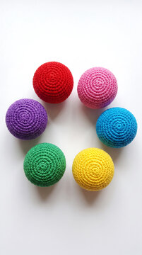 Colorful crocheted balls arranged in a circle on a plain background