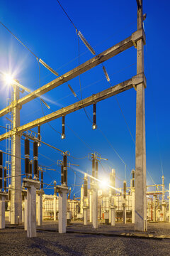 An illuminated electrical substation featuring high voltage equipment, transformers, and concrete support structures at twilight in Brazil.