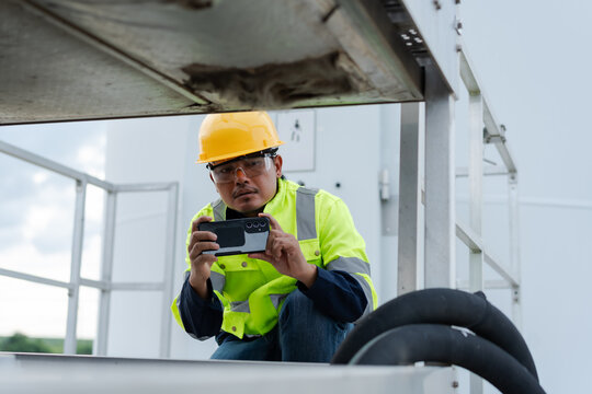 Wind turbine technician photographing equipment with a smartphone during maintenance inspection, documenting machinery condition for digital reporting, diagnostics and renewable energy service.