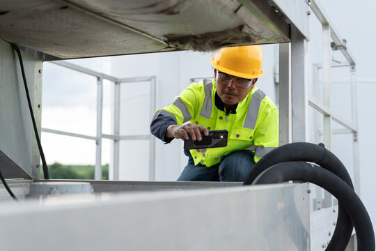 Industrial technician recording equipment condition with a smartphone during maintenance inspection, representing digital monitoring, field diagnostics, asset management and engineering reliability.