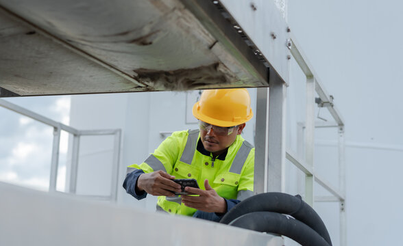 Industrial maintenance technician using a smartphone to inspect mechanical equipment, documenting condition and supporting digital diagnostics, preventive service and workplace safety operations.