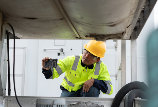 Maintenance technician photographing industrial equipment with a smartphone during inspection, documenting machinery condition for digital reporting, preventive service and engineering assessment.