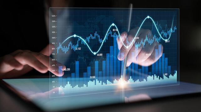 A person analyzes financial data on a tablet, showcasing virtual graphs and charts in a dark setting, highlighting the fusion of technology and business insights. Scalp