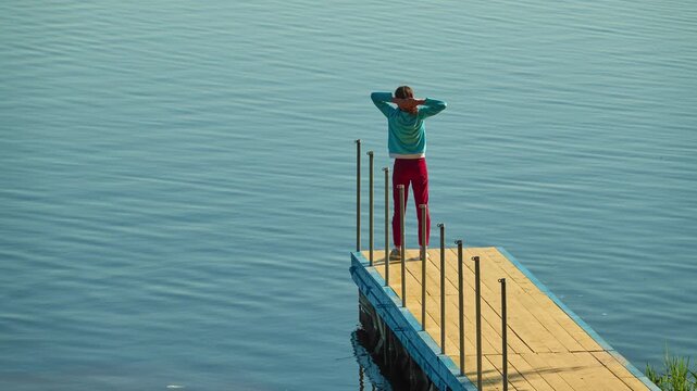 Beautiful little girl walking on wooden bridge on lake