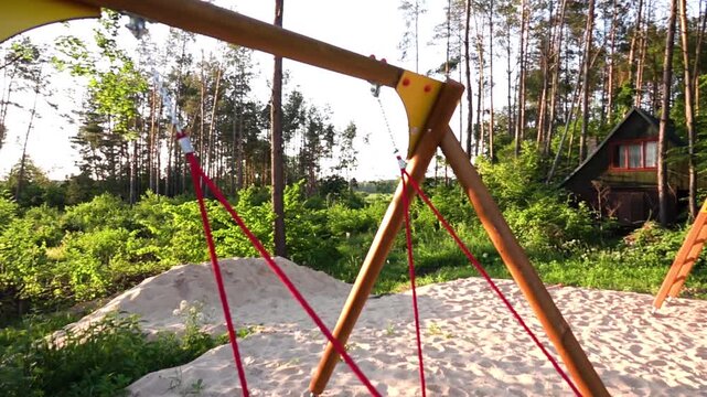 Slow motion: Teen girl rides a round swing in a city resort park. White shallow sand.